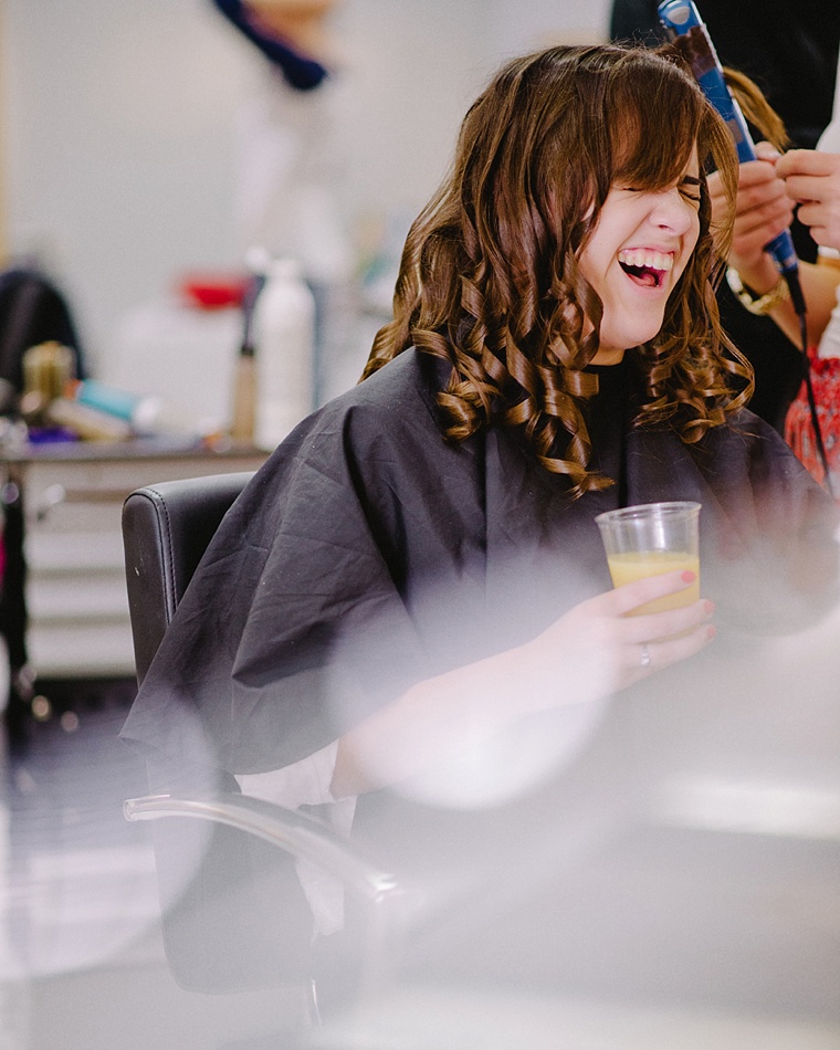 bride laughing while getting her hair done