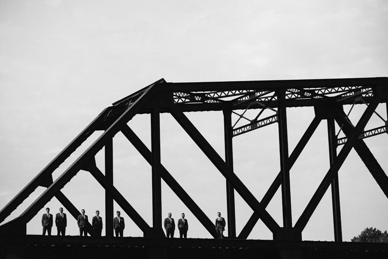 groomsmen standing on a bridge