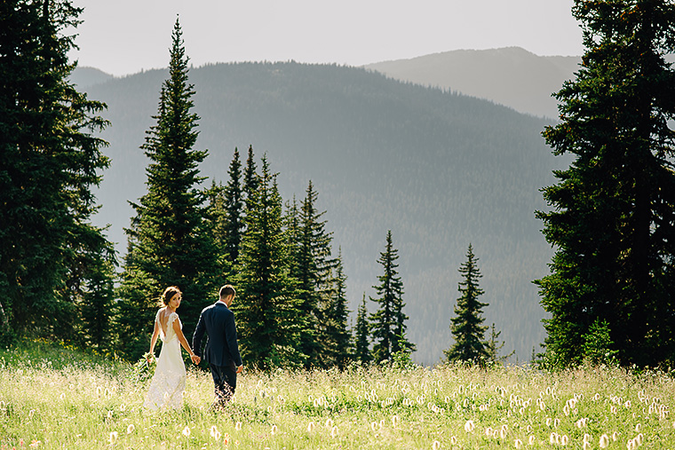 bride and groom walking through field in the forest