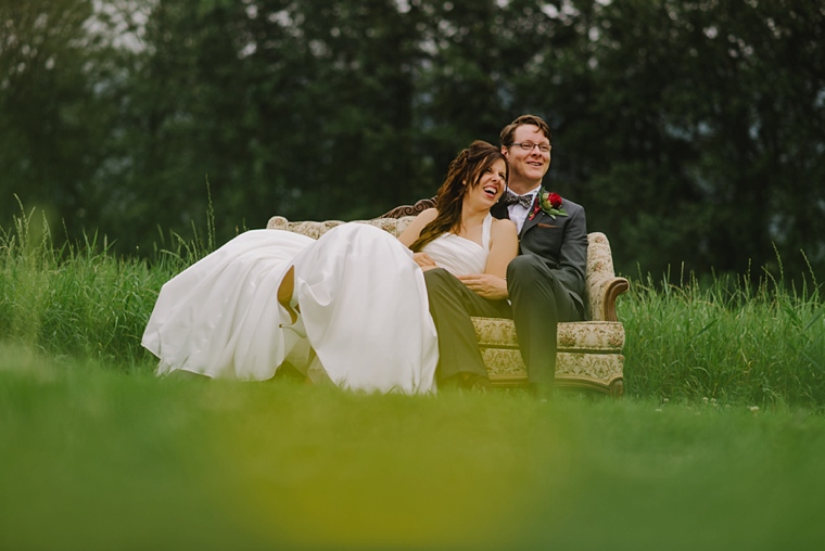 bride and groom sitting on a sofa in a field