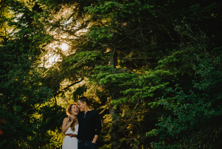 couple laughing walking through forest